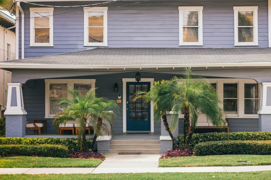 A pale blue coastal cottage with palms across the front elevation