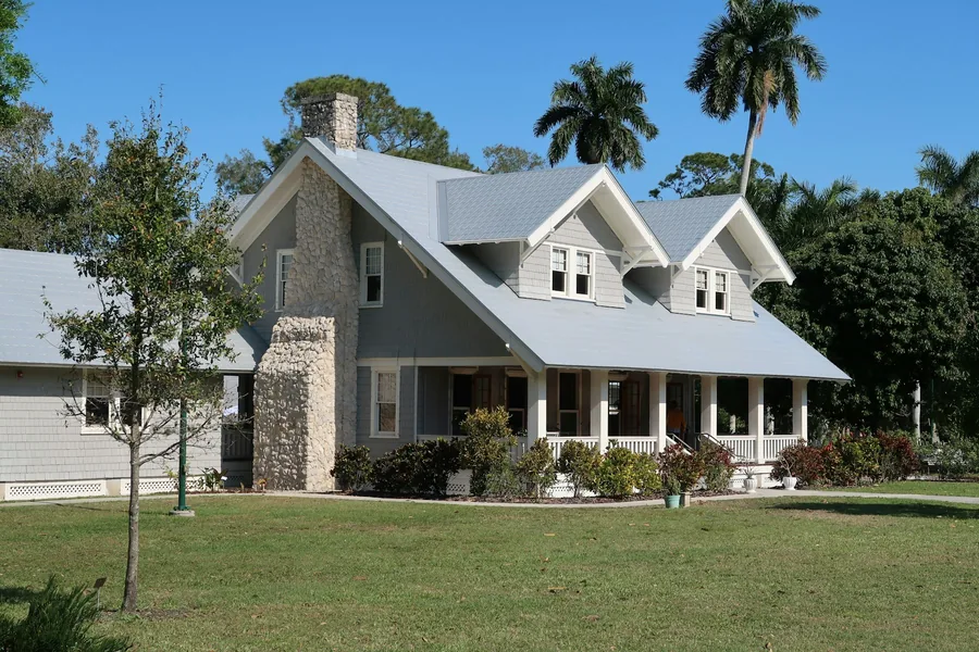 A grey Florida house with a stone chimney and a covered front porch
