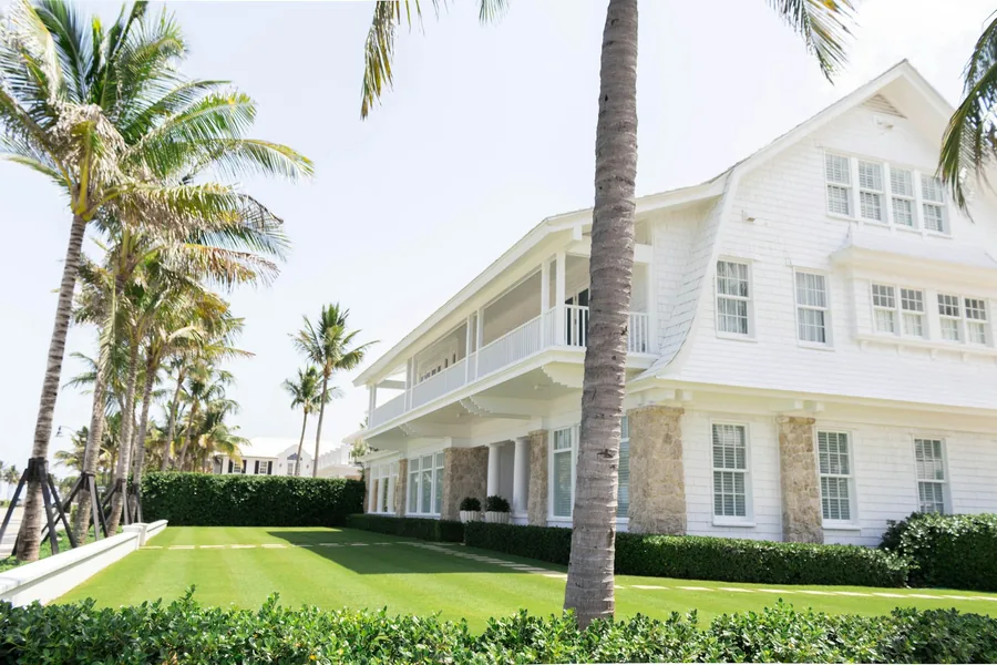 A white timber house framed by mature palm trees
