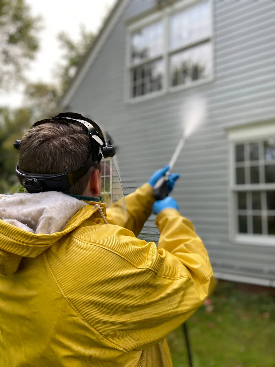 Lap siding being soft washed, the spray fanned across the boards
