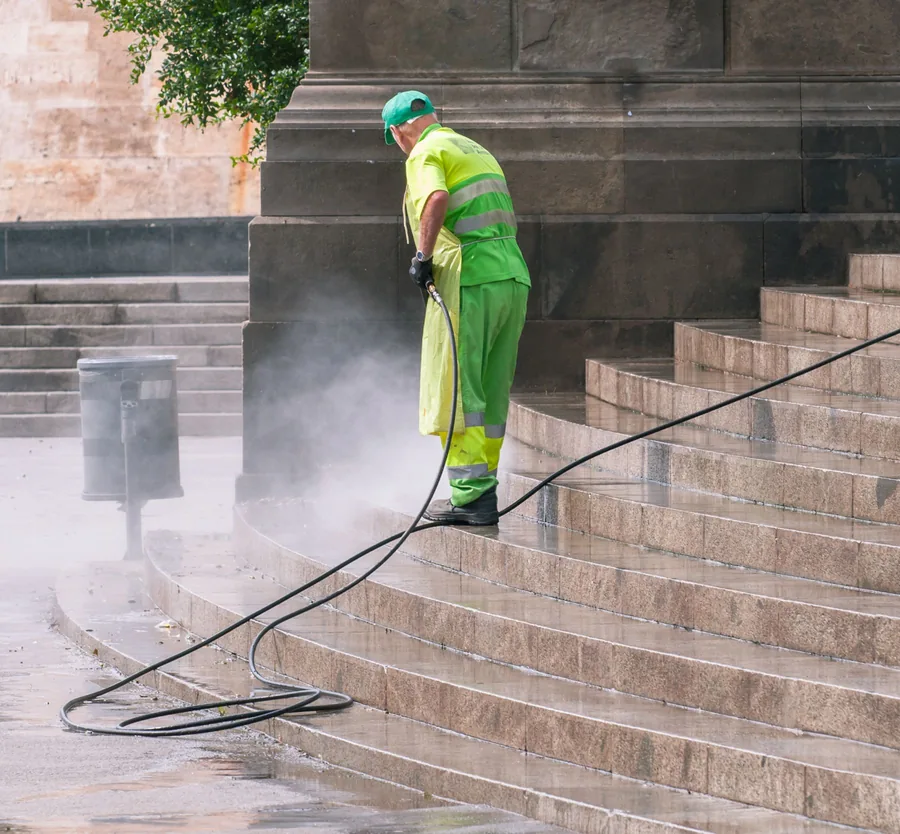 Stone steps being pressure washed, spray lifting the grime off the treads