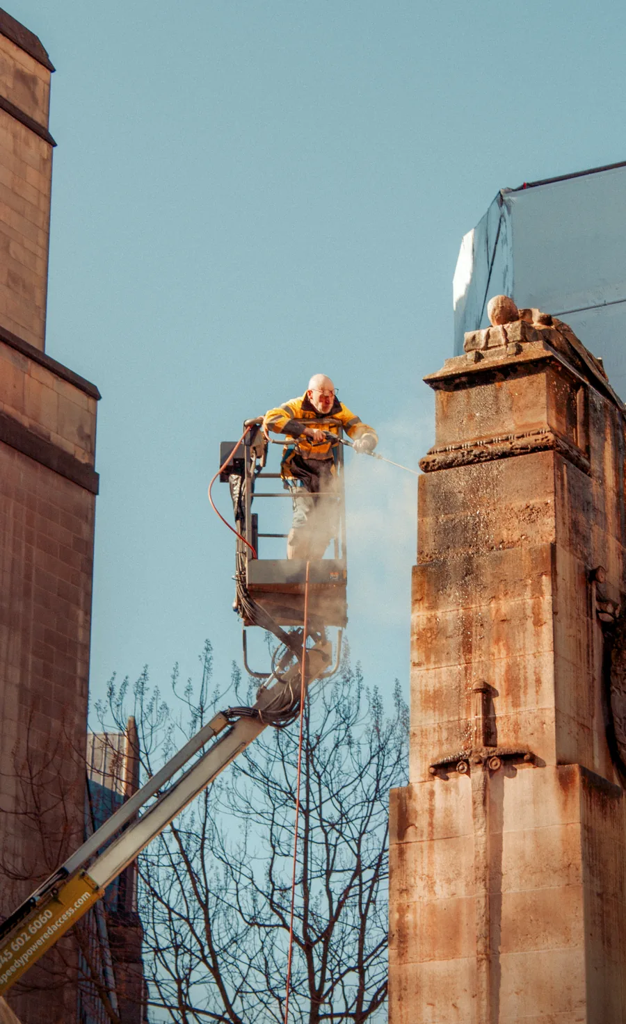 Stonework being jet washed, the cleaned band showing against the soiled surface